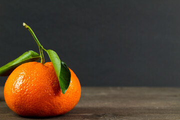 Tangerine with green leaves on black background