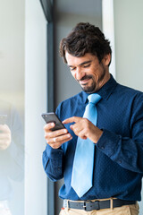 Wall Mural - Businessman smiling, holding and looking at his smartphone. Happy successful male portrait 