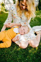 Wall Mural - Young mother posing with sun on the grass