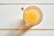 A cup of beef bone broth on a white wooden background, top view