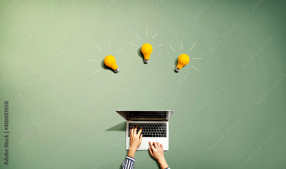 Person using a laptop computer with three light bulbs from above - obrazy, fototapety, plakaty 
