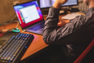 it developer programmer working and coding on his worplace at home, laptop and desktop monitor pc wi
