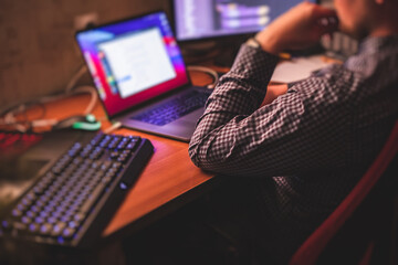 IT developer programmer working and coding on his worplace at home, laptop and desktop monitor pc with coding software program app, remote working from home, warm evening image