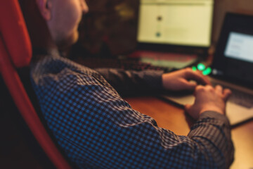 it developer programmer working and coding on his worplace at home, laptop and desktop monitor pc wi