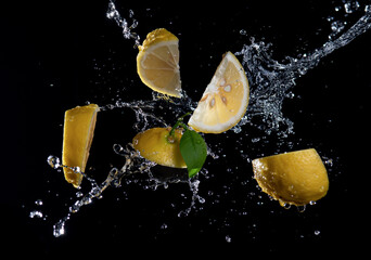 Wall Mural - slices of lemon with splash water isolated on black background.