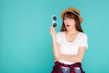 Wall Mural - Beautiful portrait young asian woman wear hat and holding sunglasses excited and surprise journey summer trip in vacation isolated on blue background, tourist asia girl amazing with travel.