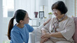 © ChayTee - Young asian woman or nurse home care hand on senior grandmother shoulder give support empathy to elderly lady or older people in assisted living homecare mental health sick relief concept.
