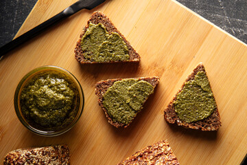 Closeup on sliced triangle flourless diet grain bread spread with pesto sauce