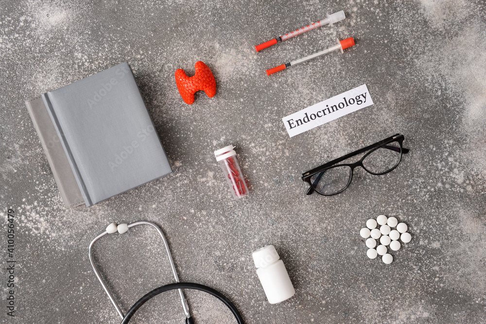 Word ENDOCRINOLOGY, thyroid gland, syringes, stethoscope and pills on grey background