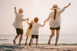 © Garun Studios - Asian family vacation holiday, Happy family running on the beach in the evening. Back view of a happy family on a tropical beach and a car on the side. Mother, father, children on the sea at sunset.