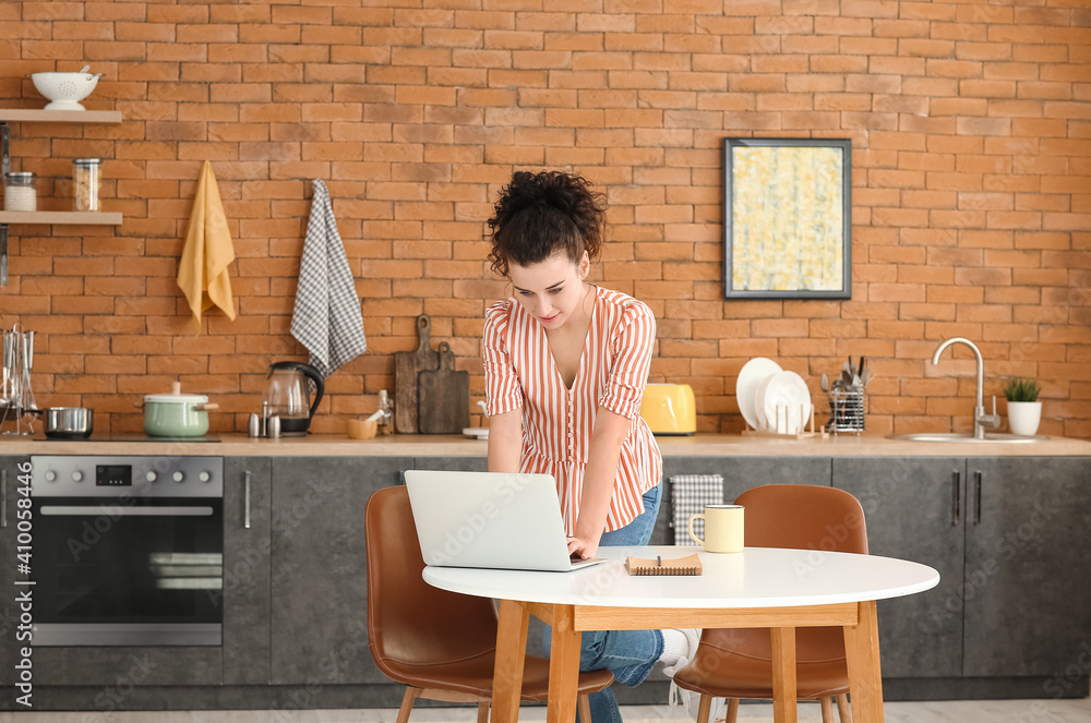 Young woman with laptop in kitchen