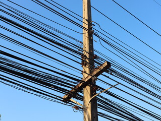 Power lines and communication cables on electric poles Bright sky background