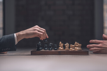 Players hand with black pawn over chessboard