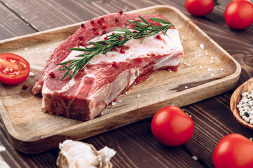 Raw beef steak with rosemary and spices on wooden board