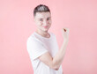 © Studio Nova - Cheerful smiling sporty man in white t-shirt flexing biceps and looking at camera isolated on pink background
