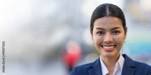 Portrait of smiling business woman while standing in front of modern office buildings © Naypong Studio