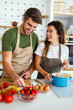 Young happy couple is enjoying and preparing healthy meal in their kitchen