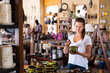 © JackF - Young positive woman choosing ceramic products in pottery store