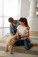 Wall Mural - Happy family playing with their dog at home. People animal pet love concept