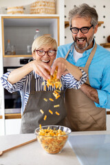 Wall Mural - Happy senior couple cooking together and having fun in home kitchen