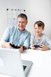 © epiximages - Family and childhood concept. Dad and son have fun together while they play a computer game.
