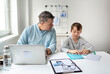 © epiximages - Business man works from home doing homeoffice and his son has homeschooling during corona crisis