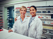 © StratfordProductions - Portrait of happy young female pharmacist with senior colleague smiling at the camera