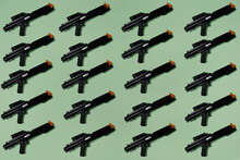 Pattern Created Of Black Rifle Toys. A Top View With Pastel Green Background.