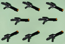 Pattern Created Of Black Rifle Toys. A Top View With Pastel Green Background.