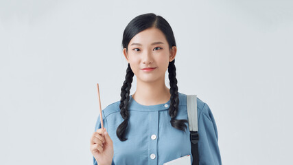 Wall Mural - Cheerful young asian teen girl with backpack have an idea and holding notebook isolated on a white background