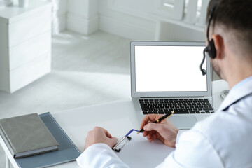 Wall Mural - Doctor with headset consulting patient online at desk in clinic, space for text. Health service hotline