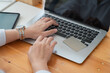 © Songsak C - Female hands typing on laptop keyboard on wooden table in the office room.