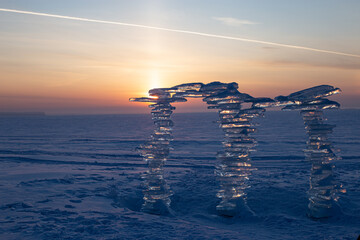 Wall Mural - a sculpture made of pieces of ice against the backdrop of a sunset, on the shore.