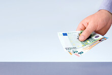 Male Hand Holding Euro Banknotes Against Gray Background With Copy Space. Buying Concept.