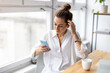 © pikselstock - Creative business woman using smartphone in loft office