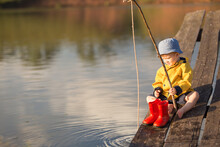 Little Boy Catching A Fish From Wooden Dock