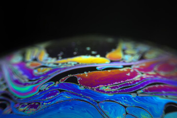 Wall Mural - macro picture of half soap bubble on black ground look like abstract psychedelic color planet in spa