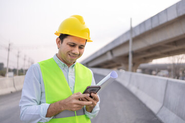 asian engineer worker using smartphone at construction site