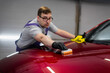 © romankosolapov - Man worker of car detailing studio applying ceramic coating on car paint with sponge applicator