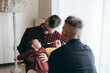 © Davide Zanin - Male gay couple with adopted baby girl at home - Two handsome dads feed the baby girl on kitchen - Male babysitters - Lgbt family at home - Diversity concept