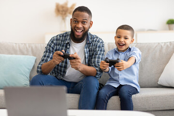 Wall Mural - Black Boy And His Dad Playing Videogame Having Fun Indoors