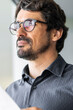 © Joao - Businessman wearing glasses holding paper document contract. Success man portrait looking through the window at the office