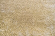 Surface of beige carpet. Frieze wool material carpeting.