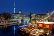 Illuminated Berlin at winter night against the Spree river, historical harbor in the downtown with old boats 