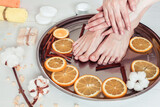 Fototapeta Las - pedicure and manicure in the spa salon with sliced oranges, cinnamon and cotton