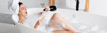 Cheerful Woman Pouring Champagne In Glass In Bathtub With Lather, Banner