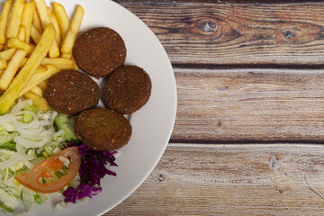 Canvas Print - Top view of falafels on a plate with french fries and salad