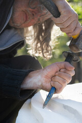 Wall Mural - Senior artist carving precise curves in white marble stone