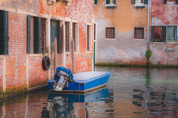 Wall Mural - Bright, colourful Venetian architecture with a parked boat over a calm canal during a quiet morning in a secluded residential area of old town Venice, Italy.