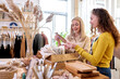 © Roman - female customers examining stack of organic clothing and cotton colors in eco-friendly shop showroom. light modern eco friendly fabric shop
